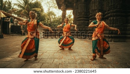 Portrait of Three Expressive Young Indian Dancers Performing Folk Dance Choreography in an Ancient Temple. Women in Traditional Clothes Dancing Bharatanatyam in Colourful Sari