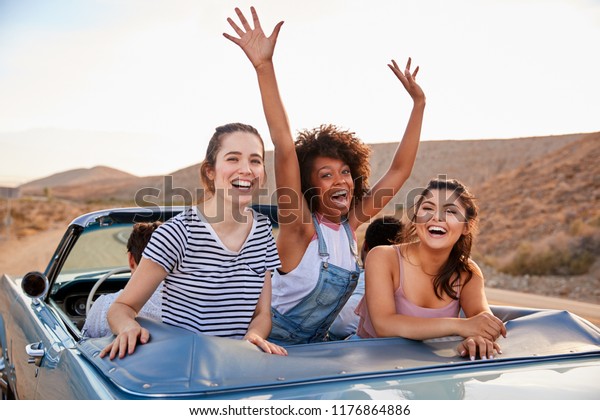 Portrait Of Three Female Friends Enjoying Road Trip\
In Open Top Classic\
Car