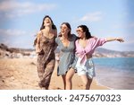 Portrait of three female friends looking at camera on the beach having fun.