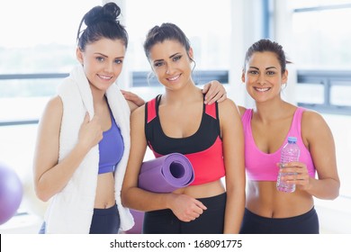 Portrait of three fit young women smiling in a bright exercise room - Powered by Shutterstock