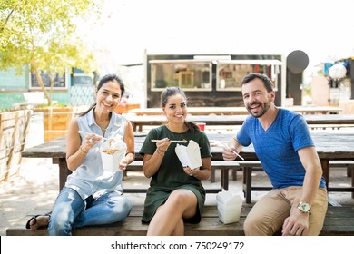 Portrait Of Three Friends Eating Takeout Oriental Food And Having A Good Time Together