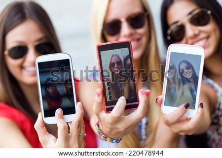 Portrait of three friends taking photos with a smartphone