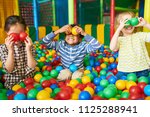Portrait of three funny little kids playing in ball pit and enjoying time in childrens entertainment and play area, copy space