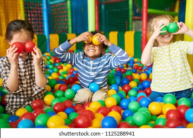 Portrait of three funny little kids playing in ball pit and enjoying time in childrens entertainment and play area, copy space - Shutterstock ID 1125288941