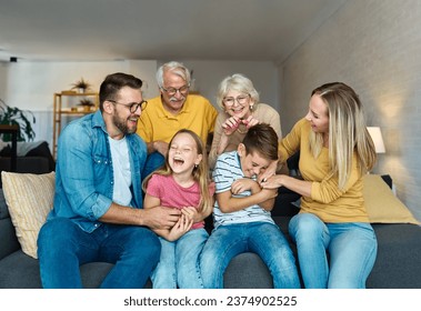 Portrait of a three generation famili, grandparents, parents and children sitting on sofa and having fun posing at home - Shutterstock ID 2374902525