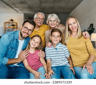 Portrait of a three generation famili, grandparents, parents and children sitting on sofa and having fun posing at home - Powered by Shutterstock