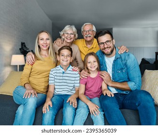 Portrait of a three generation famili, grandparents, parents and children sitting on sofa and having fun posing at home - Powered by Shutterstock