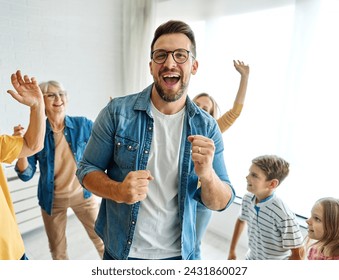 Portrait of a three generation famili, grandparents, parents and children playing and having fun dancing at home - Powered by Shutterstock