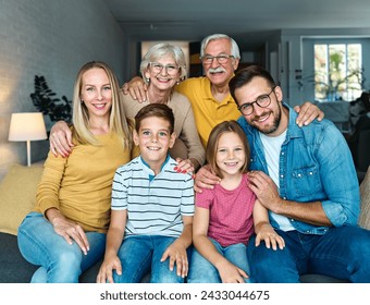 Portrait of a three generation famili, grandparents, parents and children sitting on sofa and having fun posing at home - Powered by Shutterstock