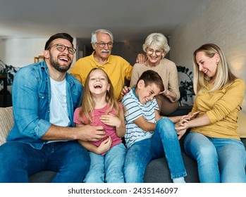 Portrait of a three generation famili, grandparents, parents and children sitting on sofa and having fun posing at home - Powered by Shutterstock