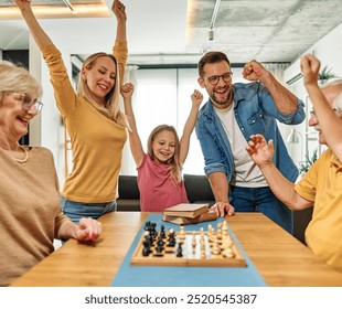 Portrait of a three generation family, grandparents, parents and children playing chess and having fun at home - Powered by Shutterstock