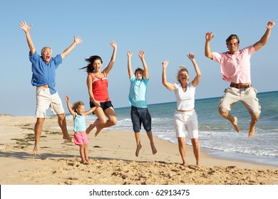 Portrait Of Three Generation Family On Beach Holiday Jumping In Air