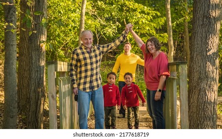 Portrait Of Three Generations Of Mixed Race Family In Midwestern Park In Autumn; White Grandparents In Foreground; Two African American Twin Boys Behind Them 