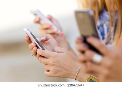 Portrait of three girls chatting with their smartphones at the park 