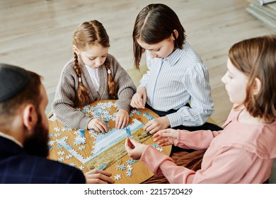 Portrait Of Three Girls In Jewish Family Playing Puzzle Game Together At Home