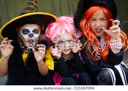 Portrait of three Halloween girls looking at camera with frightening gesture