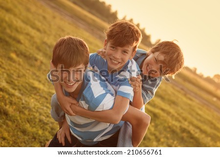 Portrait of three happy cheerful brothers at sunset, outdoor