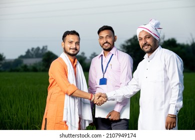 Portrait Of Three Happy Indian Mustache Men Standing Together In Field In Evening Looking On Camera With Laptop, Shaking Hands, Smiling Group Of Males In Crop Land, Greenery, Blur Background.