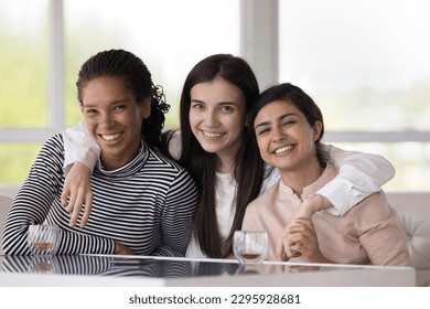 Portrait of three happy multi ethnic beautiful girls, Caucasian, African and Indian best girls friends hugging smile look at camera, enjoy trustworthy, strong friendship, understanding, showing unity - Powered by Shutterstock
