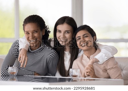 Portrait of three happy multi ethnic beautiful girls, Caucasian, African and Indian best girls friends hugging smile look at camera, enjoy trustworthy, strong friendship, understanding, showing unity Foto stock © 
