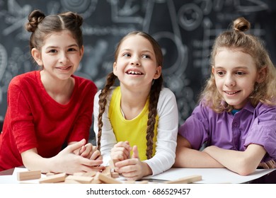Portrait of three kids in row smiling cheerfully posing against blackboard in development center - Shutterstock ID 686529457