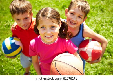 Portrait of three little children with balls looking at camera and smiling