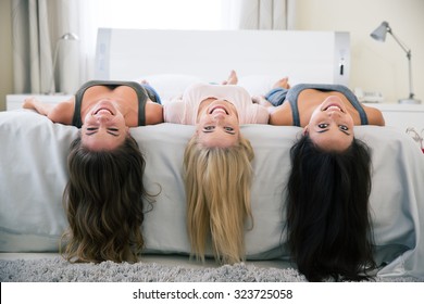 Portrait of a three smiling girls lying on the bed and looking at camera at home