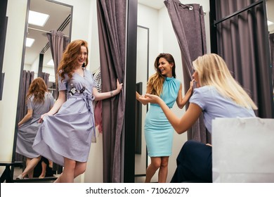 Portrait of three women trying out new clothes in the fitting room.