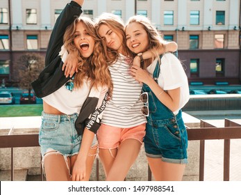 Portrait of three young beautiful smiling hipster girls in trendy summer clothes. Sexy carefree women posing on the street background.Positive models having fun.Hugging