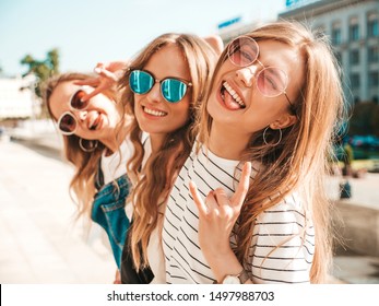 Portrait of three young beautiful smiling hipster girls in trendy summer clothes. Sexy carefree women posing on the street background.Positive models having fun in sunglasses.Hugging