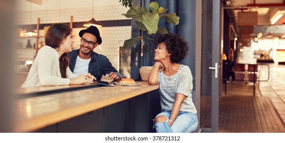 Portrait Of Three Young People Sitting Together At A Cafe. Group Of Young Friends Meeting In A Coffee Shop.