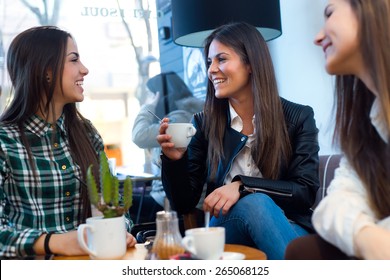 Portrait Of Three Young Woman Drinking Cofee And Speaking At Cafe Shop.