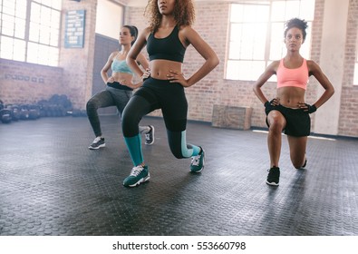 Portrait Of Three Young Women Doing Workout Together In Gym. Females Exercising In Fitness Class.