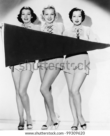 Portrait of three young women holding a banner and smiling