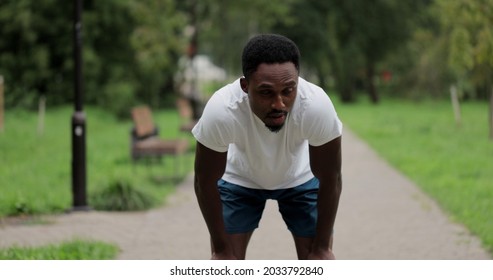 Portrait of tired black runner man breathing after run in city park. African american man athlete have break after running exercise in summer park. Close up sport man resting after workout outdoor.
