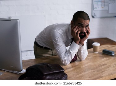 Portrait Of A Tired Businessman Leaning On His Office Desk. Real Life Businesspeople Shot On Location. Since These Locations Are The Real Thing, And Not Shot In An Office Studio, High ISO Levels Are