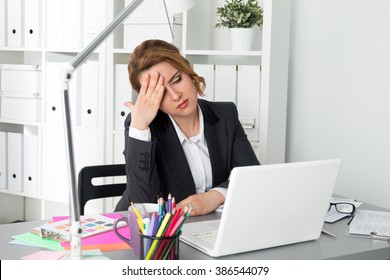 Portrait of tired businesswoman sitting at her office and touching her head. Woman trying to concentrate. Headache, problems, stress at work, overworking or deadline concept - Shutterstock ID 386544079
