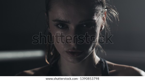 Portrait of tired female boxer standing on the\
boxing ring and looking at the\
camera