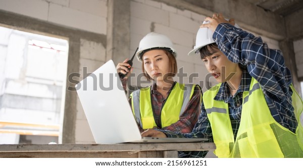 Portrait of tired industrial Engineer team working\
on laptop in civil construction site.Frustrated and stressed\
Architecture sitting at desk in workplace having problem with\
project.Problem in\
work.