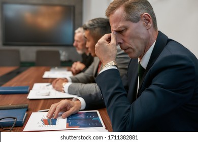 Portrait of tired mature businessman massaging his nose and keeping eyes closed while having a business meeting in the office. Stress. Business concept. Partnership. Tiredness - Powered by Shutterstock