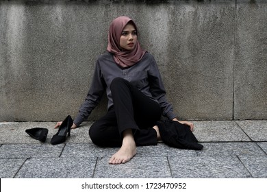 Portrait of a tired muslim woman office workers sitting at street floor after working hard.