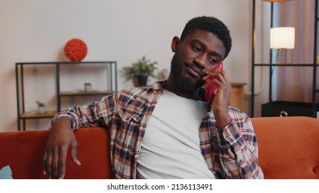 Portrait Of Tired Sleepy Man In Shirt Talking On Mobile Phone With Friend At Home. Sad African American Guy Freelancer Making Online Conversation Speaks On Smartphone Sitting On Sofa At Living Room