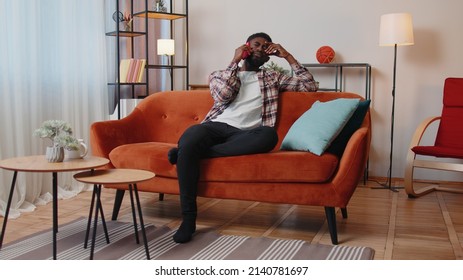 Portrait Of Tired Sleepy Man In Shirt Talking On Mobile Phone With Friend At Home. Sad African American Guy Freelancer Making Online Conversation Speaks On Smartphone Sitting On Sofa At Living Room