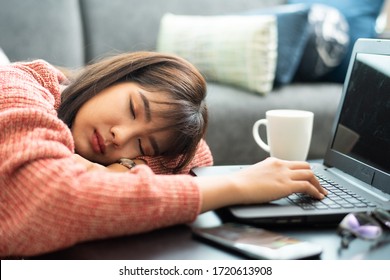 Portrait of a tired young businesswoman sitting at the table with laptop computer and sleeping