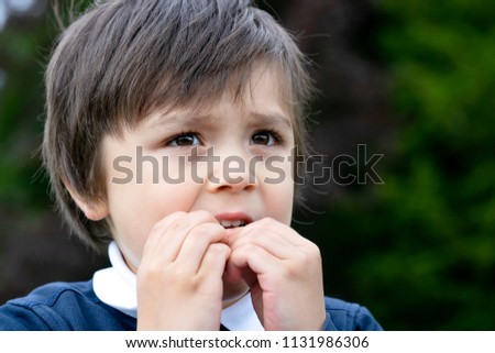 Portrait of toddler boy biting his finger nails while looking at some thing at the park, Childhood and family concept, emotional child portrait