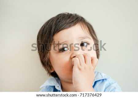 Portrait of toddler boy biting his finger nails while looking at camera in retro tone, Childhood and family concept, Emotional Child portrait,