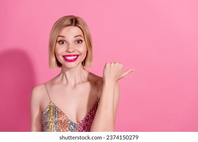 Portrait of toothy beaming girl with blond hair wear sequins dress impressed directing empty space isolated on pink color background