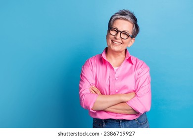 Portrait of toothy beaming person with grey hairdo wear stylish blouse in eyewear hands crossed smiling isolated on blue color background - Powered by Shutterstock