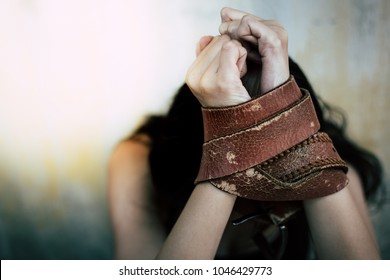 Portrait torture, depressed beautiful woman: Attractive girl feels sad, scared, fears or hopeless. Pretty poor girl tie leather belt on her arms by traffickers, kidnapper. She is crying. She is victim