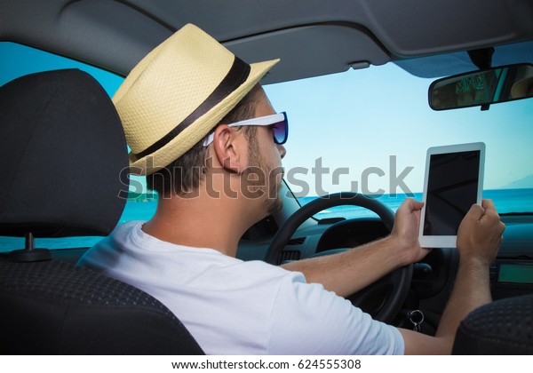 Portrait of tourist guy in car holding blank screen\
digital tablet device.\
